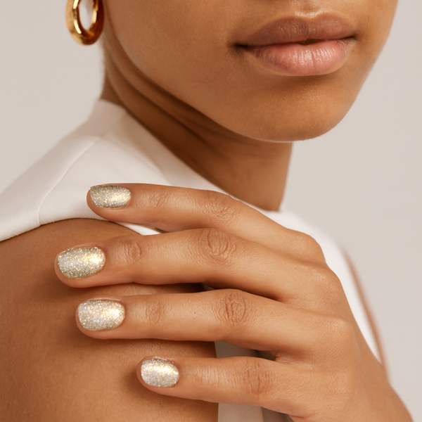 Close-up of a hand with glittery nail polish on a neutral background