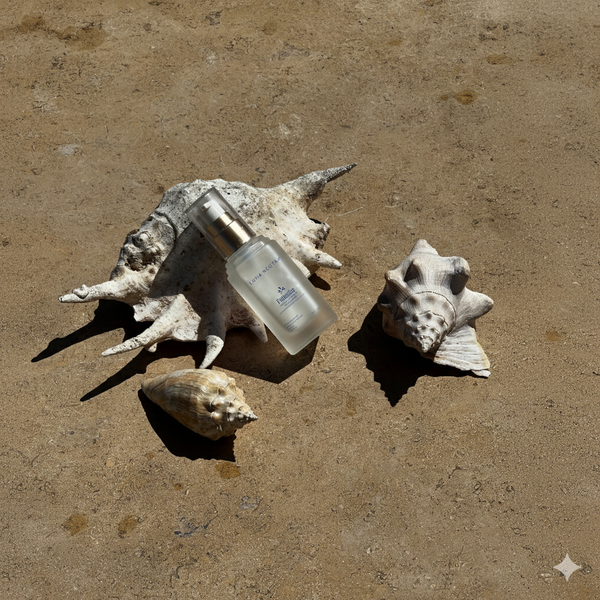 Skincare bottle with seashells on a sandy background