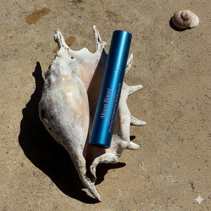 Blue cosmetic tube on a shell with sand background