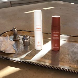Two skincare products on a decorative metal tray with natural light.