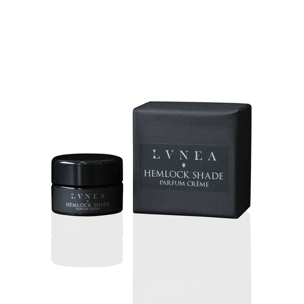 LVNEA Hemlock Shade Parfum Creme – a 10g amethyst glass pot of dark, coniferous solid perfume featuring notes of black spruce, hemlock, and fir needle, nestled in a gift box. The scent offers a rich, resinous forest blend.