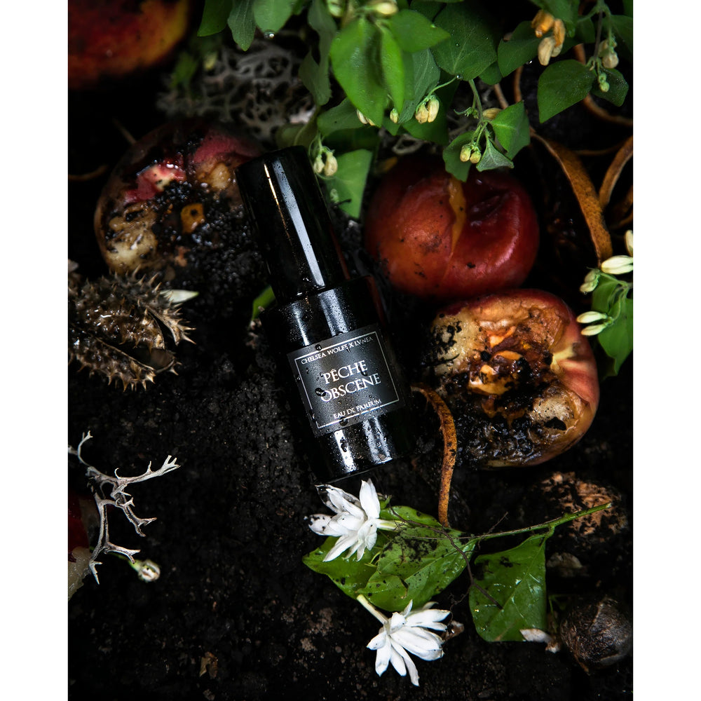 Amethyst glass bottle of LVNEA Pêche Obscène Eau de Parfum, featuring notes of peach, jasmine, and patchouli, encased in a matte black tube.