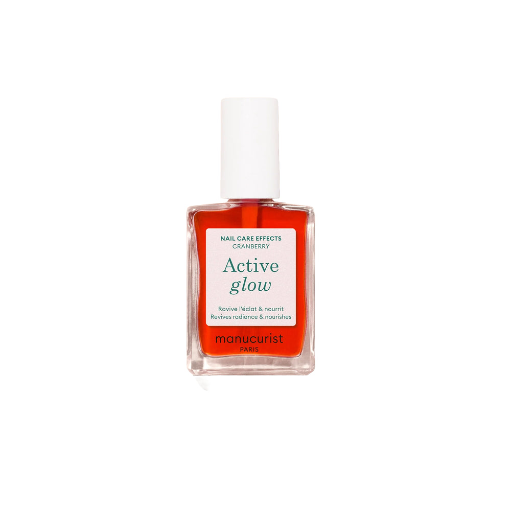 Bottle of MANUCURIST Active Glow™ Cranberry coral nail polish with a glossy, translucent finish.