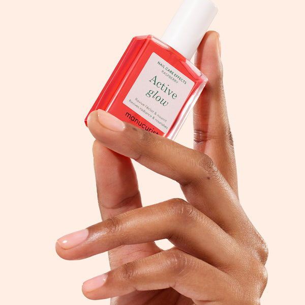 Hand holding a bottle of 'Active Glow' nail care product against a beige background
