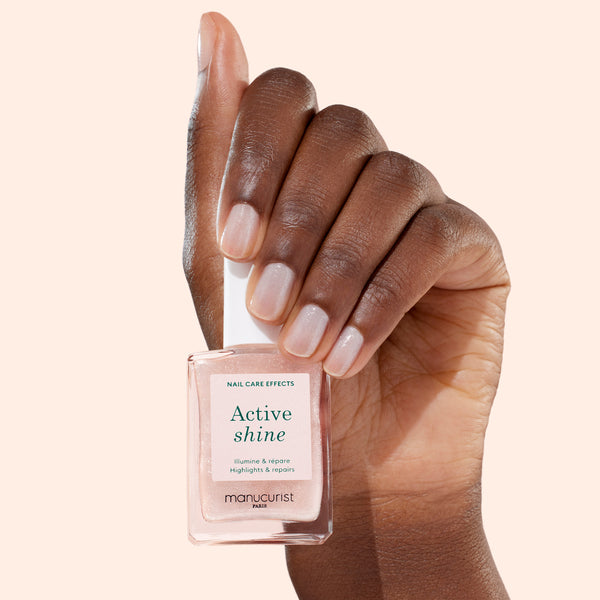 Hand holding a bottle of 'Active Shine' nail care product with a neutral background