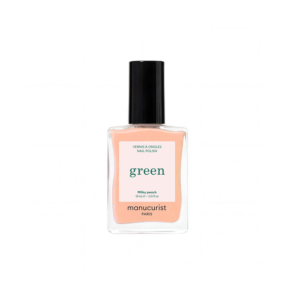 A bottle of Manucurist nail polish in the shade Milky Peach, featuring a peach-colored liquid inside a clear glass bottle with a black cap and a white label.