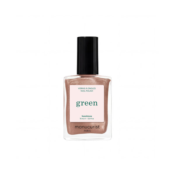 A bottle of Manucurist nail polish in the shade Sandstone, featuring a clear glass bottle filled with a shimmering sandstone-brown polish, a light pink label with green text, and a black cap, set against a plain white background.