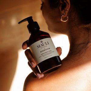 Person holding a bottle of Mauli Rituals x Dishoom Hand & Body Wash with a warm glow.