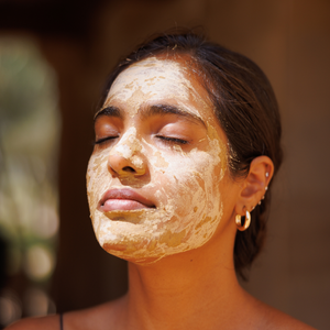 Woman with a facial mask on her face outdoors with a blurred natural background