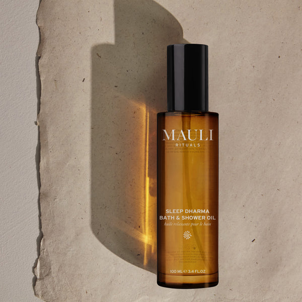 Brown bottle of MAULI Rituals Sleep Dharma Bath & Shower Oil on a textured beige background
