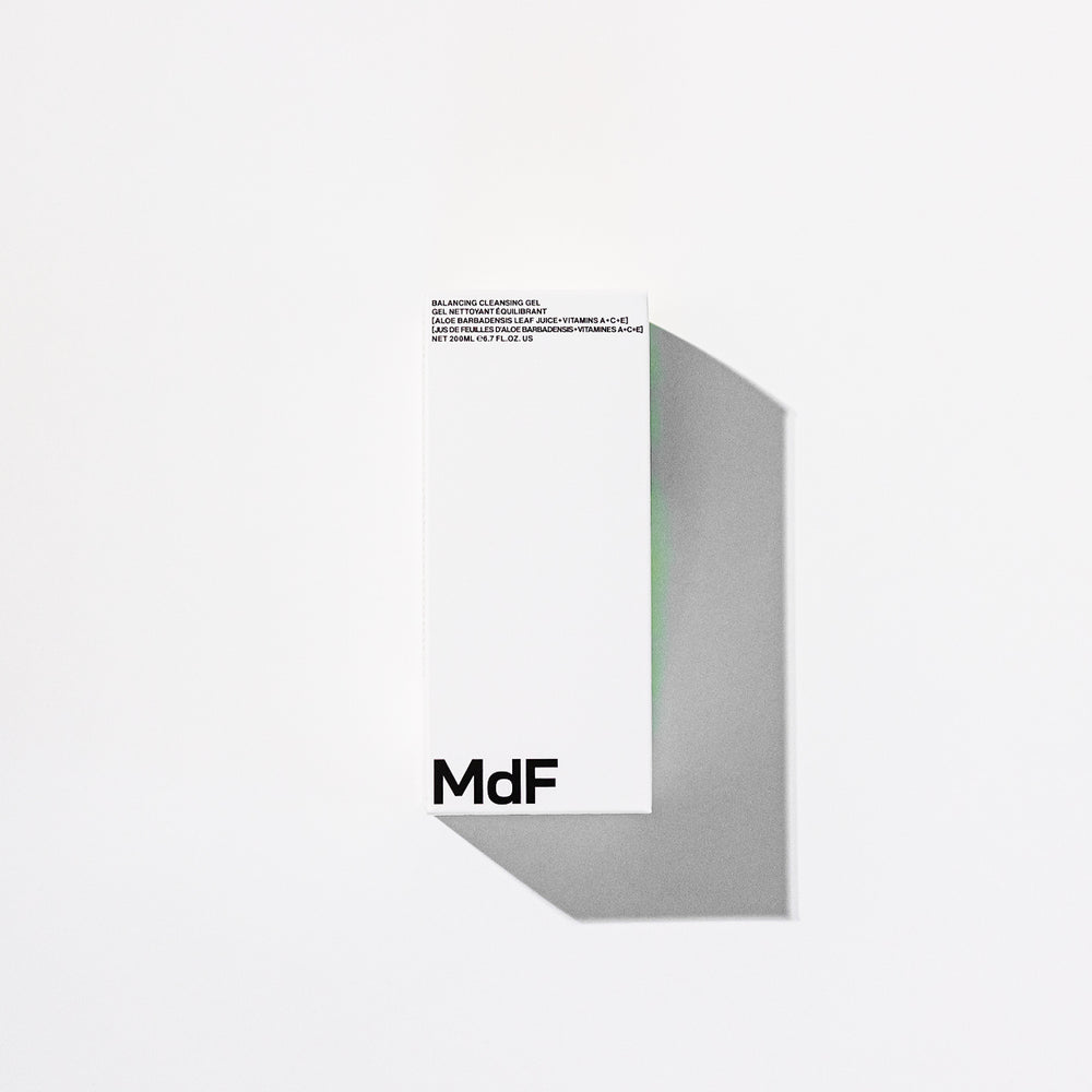 Silver bottle with black pump and 'MDF' branding on a white background
