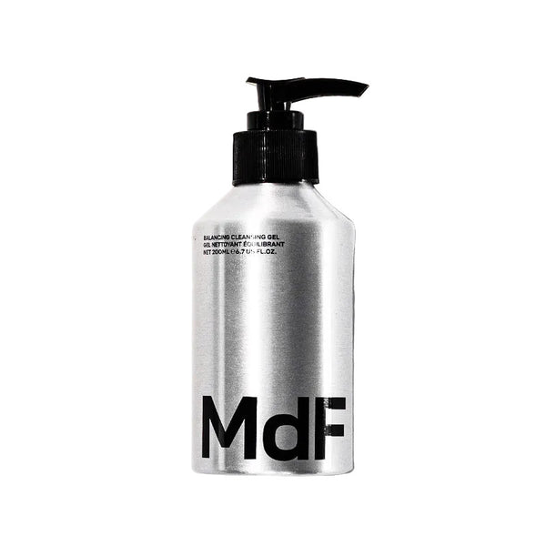 Silver bottle with black pump and 'MDF' branding on a white background