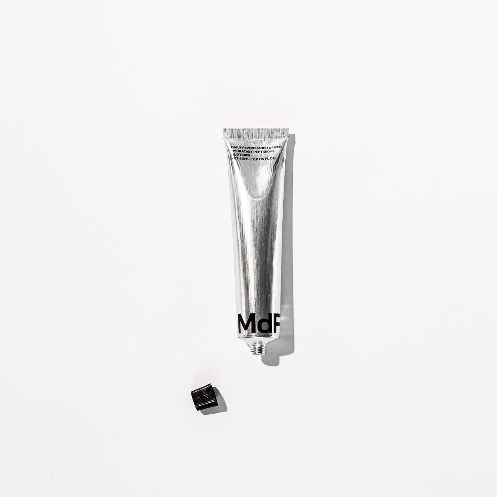 Silver tube with 'MDF' branding on a white background