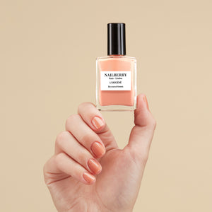 Hand holding a Nailberry nail polish bottle with a beige background