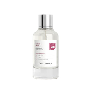 A clear glass bottle of Olfactory X Lemon + Musk Eau de Parfum with a reflective silver cap and a white label, set against a plain white background.