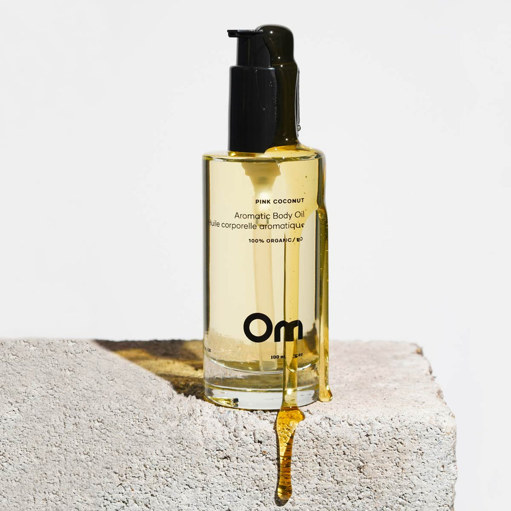Bottle of OM Organics Pink Coconut Aromatic Body Oil with a blend of meadowfoam, jojoba, and olive squalane oils for soft, radiant skin.