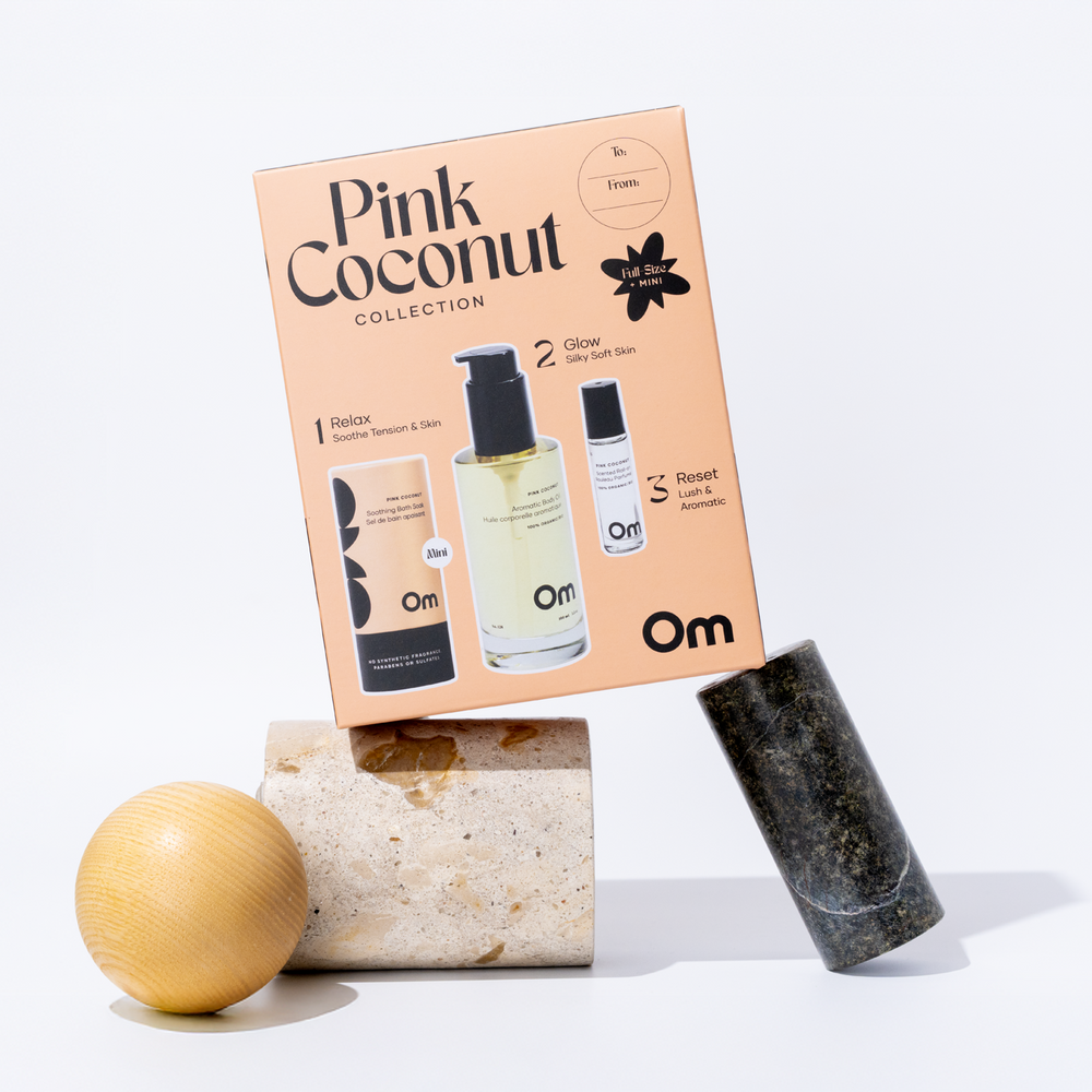 OM Organics Pink Coconut body care set with aromatic body oil, scented roll-on, and soothing bath soak displayed together.