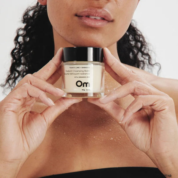 Person holding a jar of skincare product -OM ORGANICS Tahiti Lime + Babassu Radiant Cleansing Balm