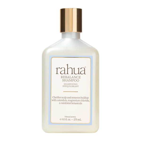 A bottle of Rahua Rebalance Shampoo with a frosted off-white body, a metallic gold cap, and a cream-colored label with a light blue border, set against a plain white background.