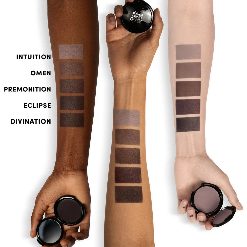 Three arms with swatches of makeup shades labeled 'Intuition', 'Omen', 'Premonition', 'Eclipse', and 'Divination'.