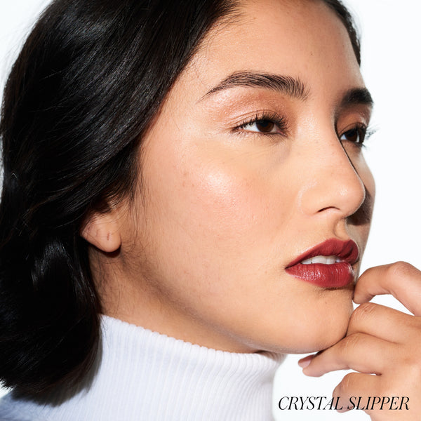 Close-up of a woman with red lipstick and a white turtleneck, with 'Crystal Slipper' blush. RMS BEAUTY Lip2Cheek. Crystal slipper