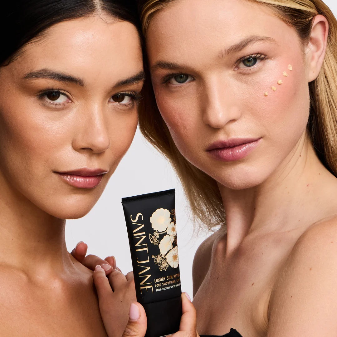 Two women holding a Saint Jane product against a neutral background. SAINT JANE Sun Ritual Mineral SPF30