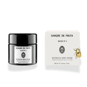 Sangre de Fruta Botanical Body Cream with a rich whipped texture, shown in black glass jar next to its packaging, on white background.