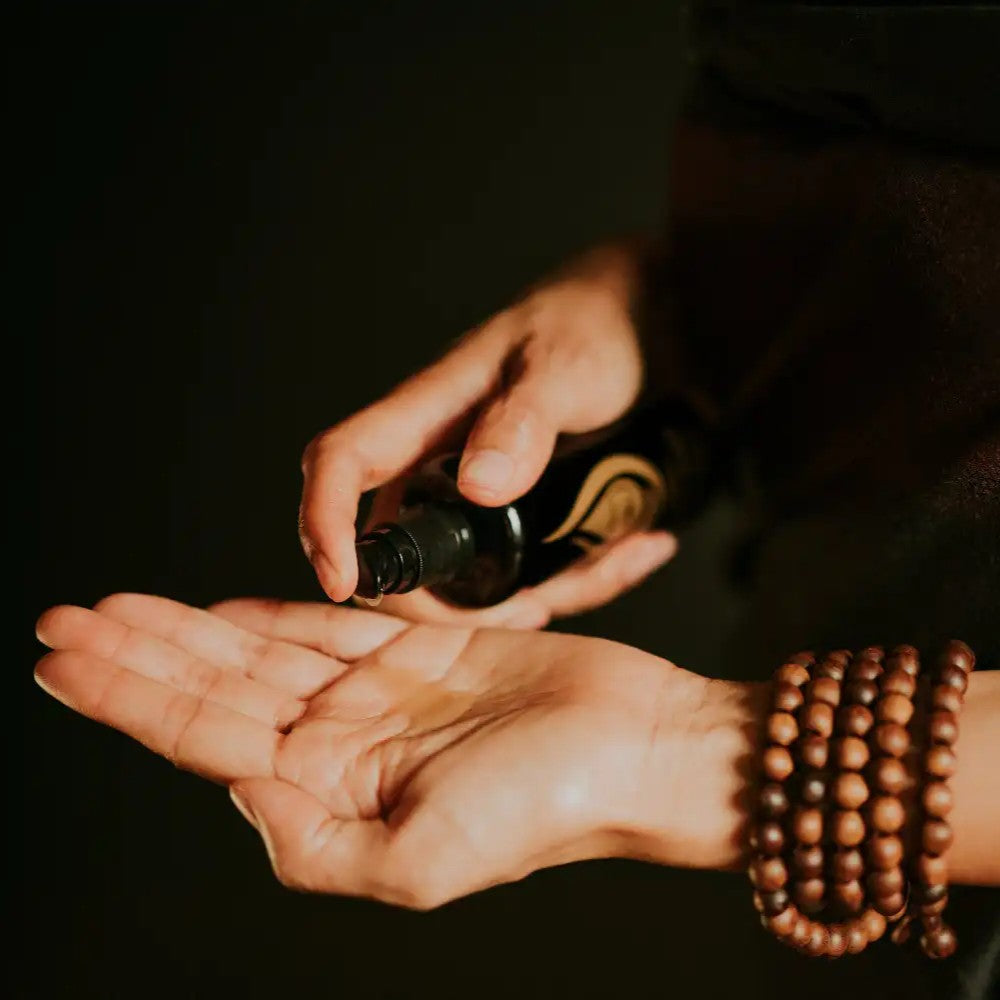 A woman applying a bottle of Siam Seas Morning Delight Cleanser and Makeup Remover to her palm against a dark background