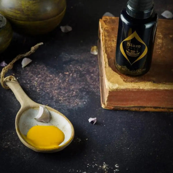 Black glass bottle with a pump of SIAM SEAS Twilight BeCalm Skin Serum next to a spoon with a serum texture on a dark surface