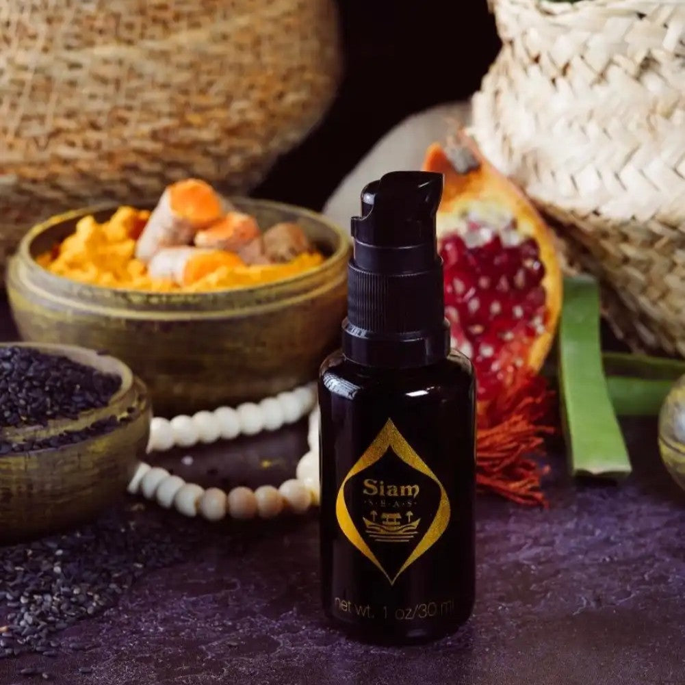 Black bottle with pump with gold logo labeled 'SIAM SEAS Twilight BeCalm Skin Serum' on a dark surface with natural elements in the background.