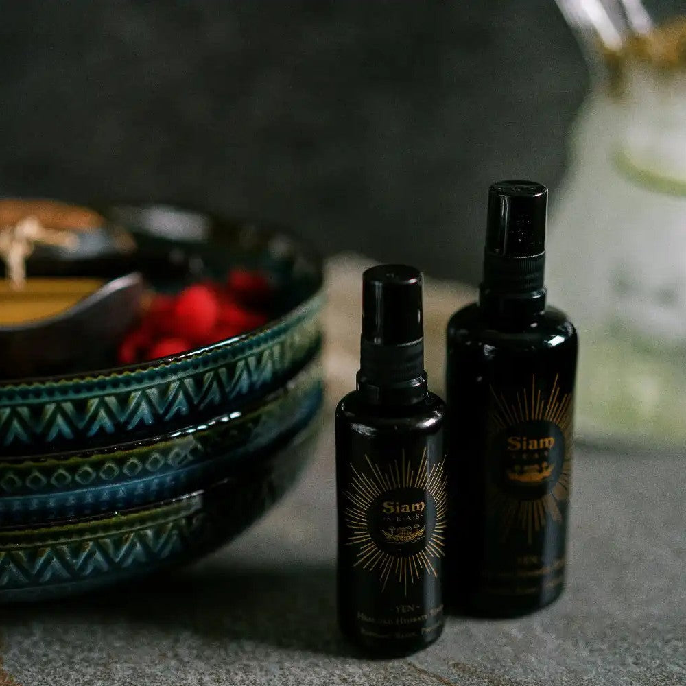Two black spray bottles SIAM SEAS Yen Essence Toner on a textured surface with bowls in the background. ALWAYS SHOW