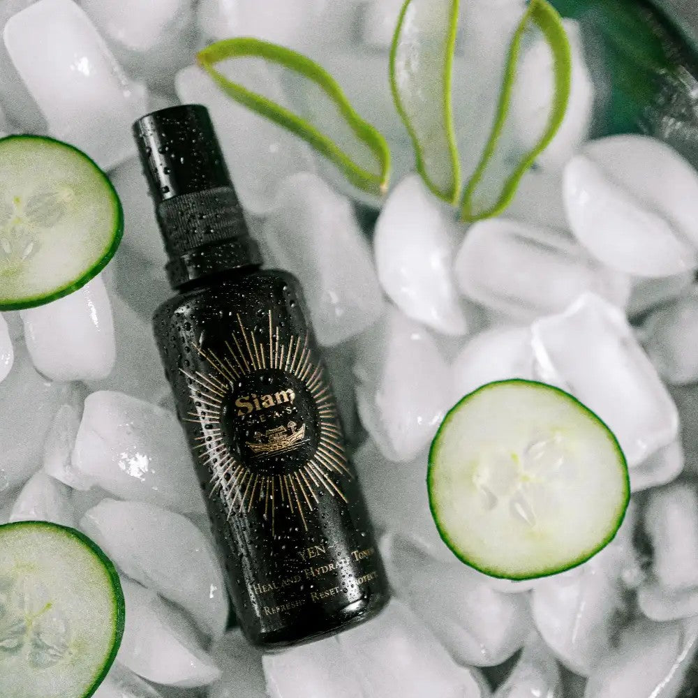 Black bottle of SIAM SEAS Yen Essence Toner with gold design on a bed of ice and cucumber slices. ALWAYS SHOW