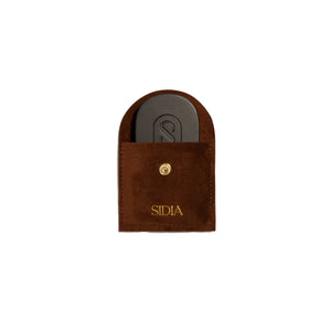 Brown pouch with a black solid perfume inside, featuring the brand 'Sidia' on the pouch, on a white background.