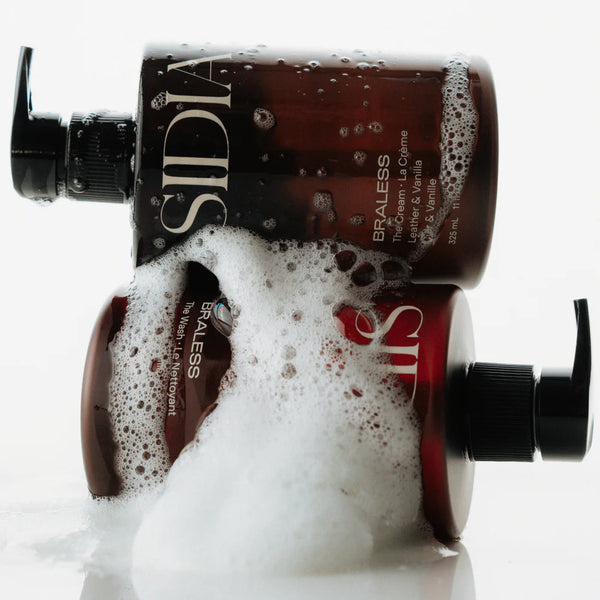 Two bottles of Sidia body washes with foam overflowing, on a white background
