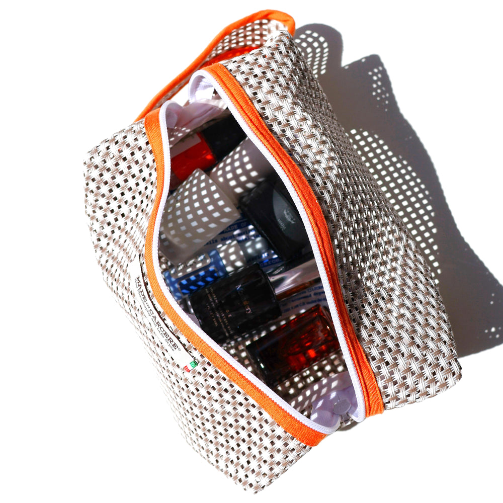 Collection of skincare and cosmetic products with a patterned pouch on a white background
