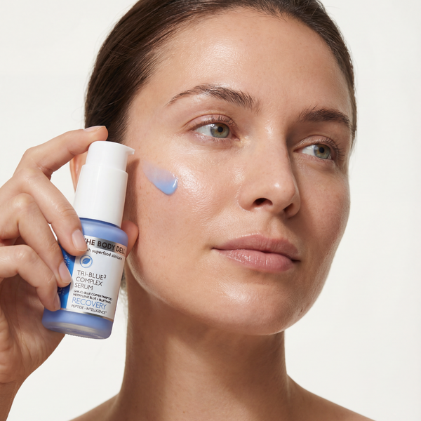 Woman applying skincare product to her face with a neutral background