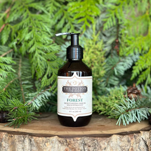 The Potion Cosmetics Forest Body Potion bottle on a natural wood surrounded by pine branches