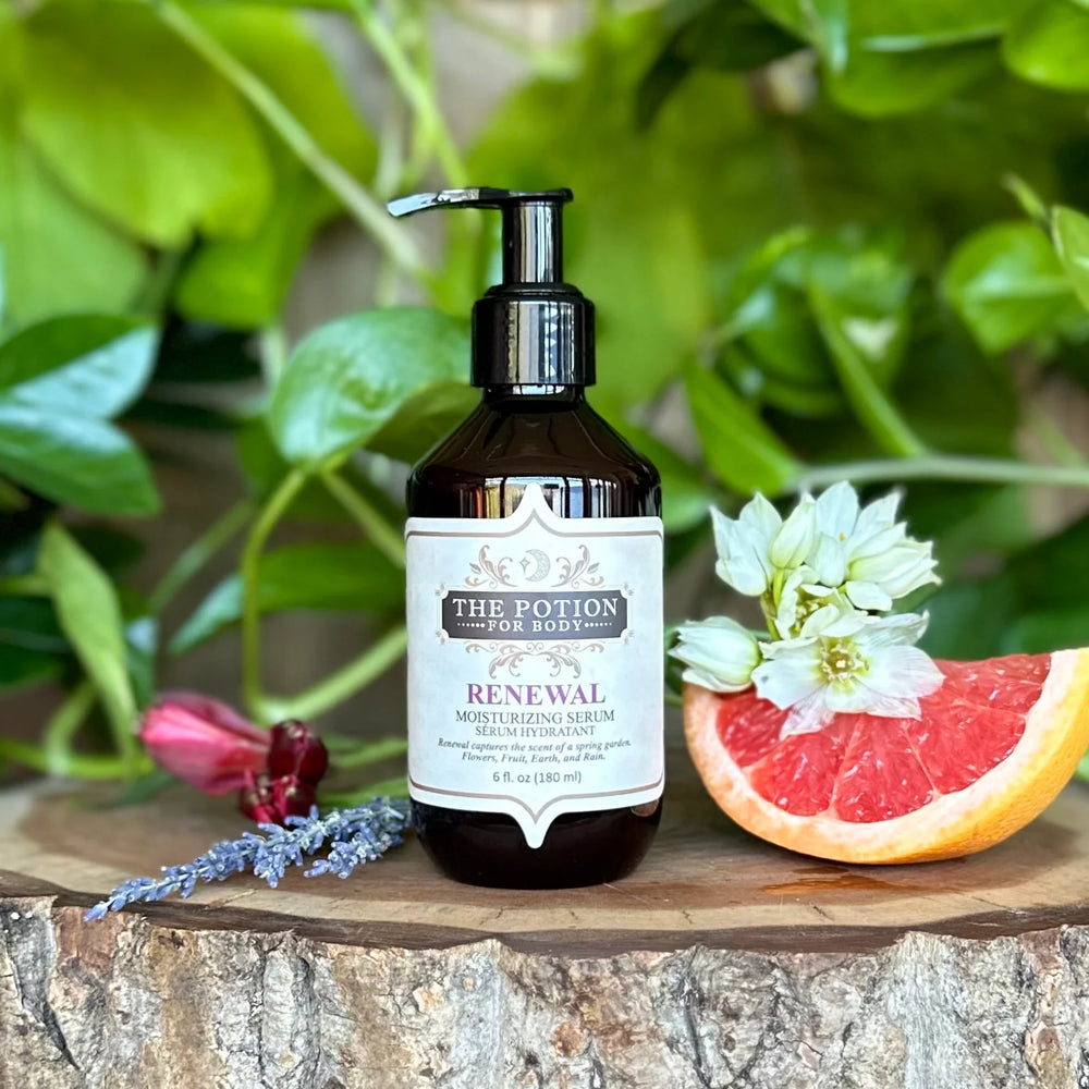 THE POTION COSMETICS Renewal Moisturizing Serum bottle surrounded by flowers and citrus, evoking a blooming garden with fresh, earthy notes.