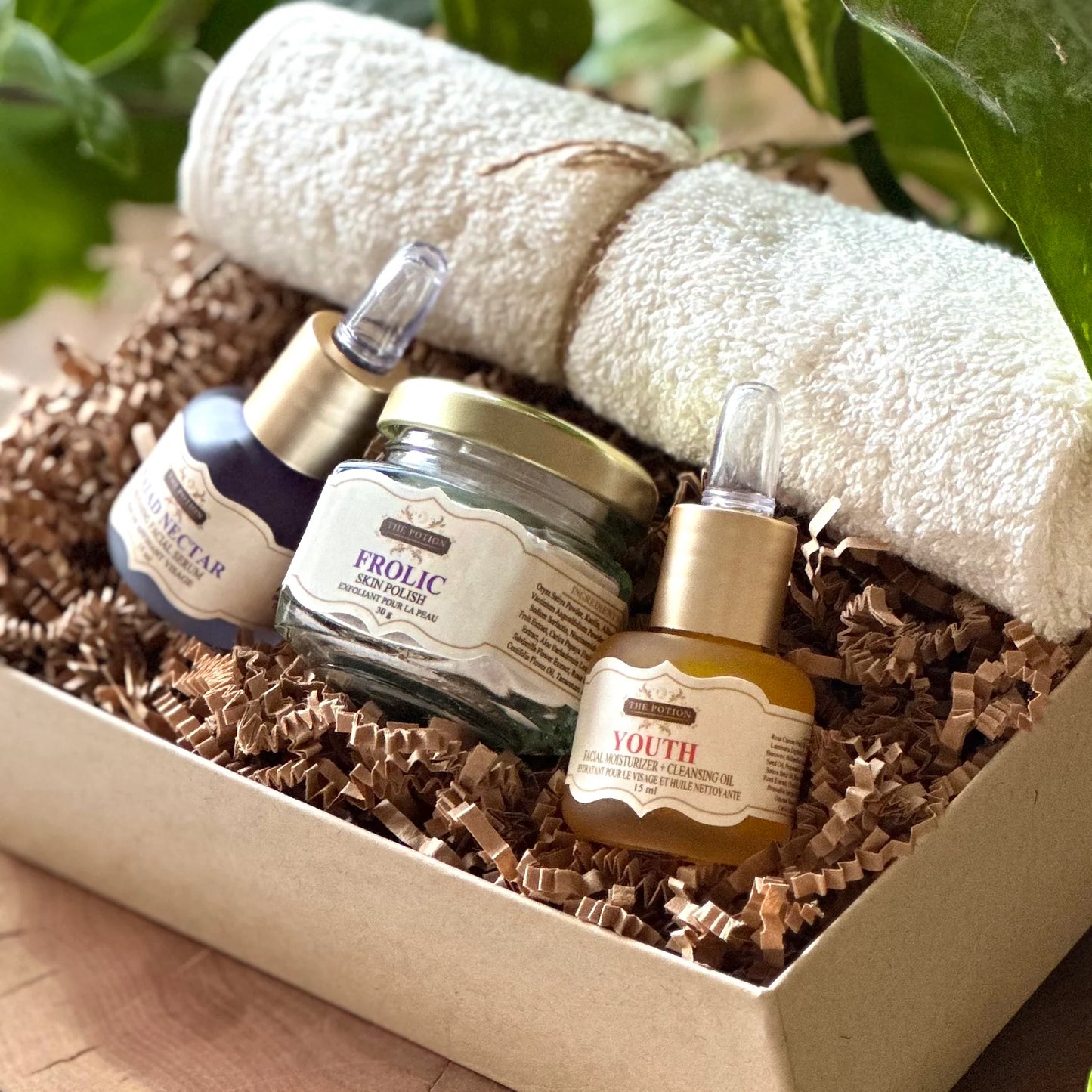 THE POTION COSMETICS The Glow Collection featuring Youth Face Potion, Naiad Nectar Refining Serum, Frolic Skin Polish, and an organic cotton face cloth arranged elegantly to highlight a radiant, glow-enhancing skincare routine.