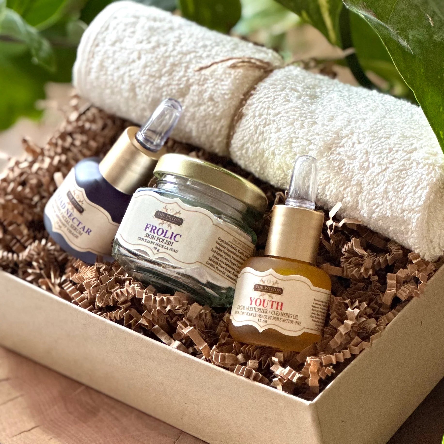 THE POTION COSMETICS The Glow Collection featuring Youth Face Potion, Naiad Nectar Refining Serum, Frolic Skin Polish, and an organic cotton face cloth arranged elegantly to highlight a radiant, glow-enhancing skincare routine.