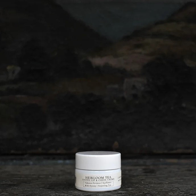 TIDELANDS HOUSE Heirloom Tea Tinted Lip & Cheek Crème in a sleek container, showcasing the burnished darjeeling tea brown hue with antique rose pearl finish, enriched with Oakmoss Ferment and Wild Hyssop Flower.