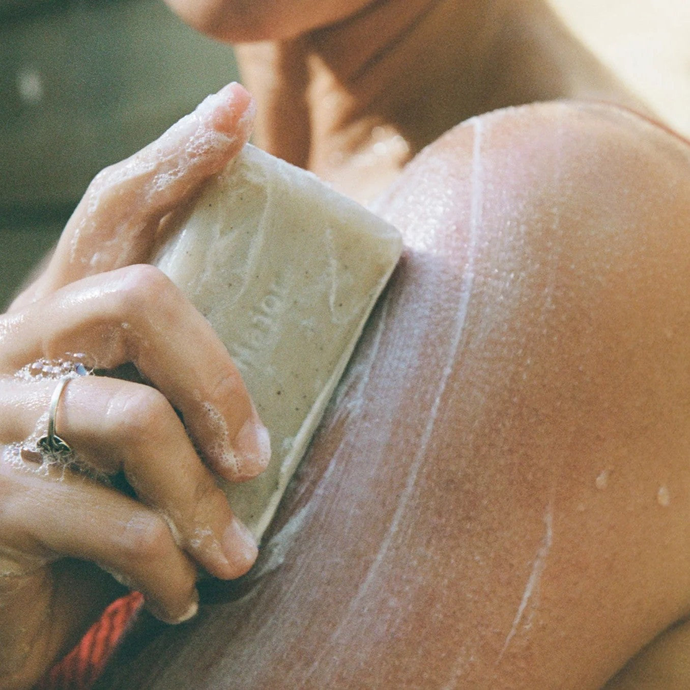 Person applying soap to their skin with a bar of soap. URSA MAJOR Hoppin’ Fresh Bar Soap