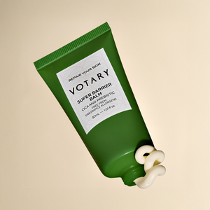Green tube of Votary Super Barrier Balm on a beige background