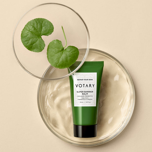 Green tube of Votary Super Barrier Balm on a beige background with leaves.