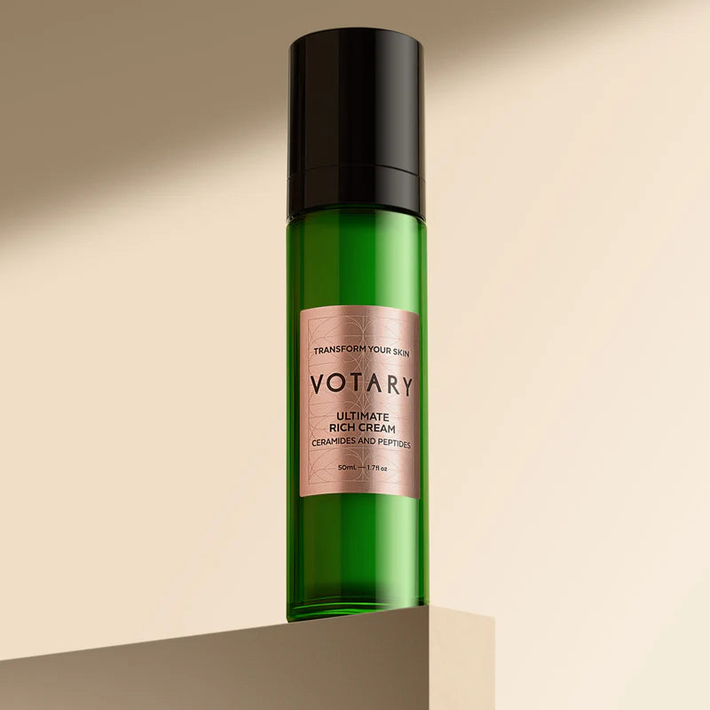 Green bottle with black cap and pink label on a beige background. VOTARY Ultimate Rich Cream