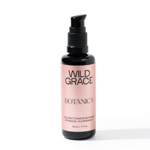 A 50 ml bottle of Wild Grace Botanica Cleansing Oil on a white background. The bottle is dark amber glass with a black pump dispenser and a dusty pink label featuring black text.