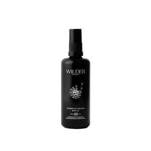 Wilder Botanics Flower of the Sun Body Oil bottle surrounded by natural elements, highlighting its woody and floral ingredients. The oil is presented in eco-friendly packaging, conveying hydration, nourishment, and wellness for all skin types.