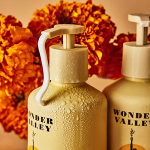 Two Wonder Valley bottles with pump dispensers against a floral background
