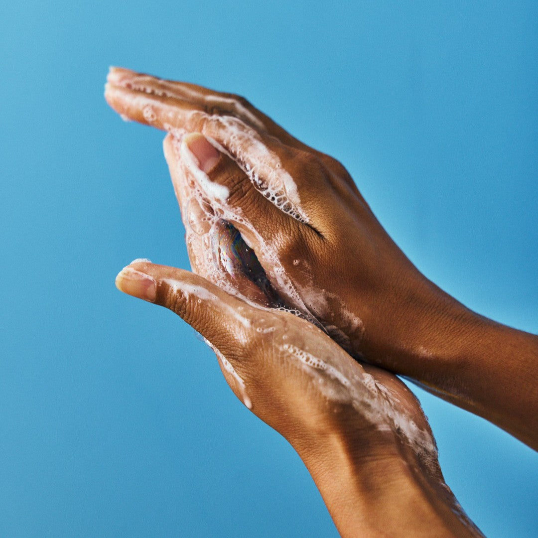 Hands with soap suds against a blue background. WONDER VALLEY Wild Garden Hand Wash