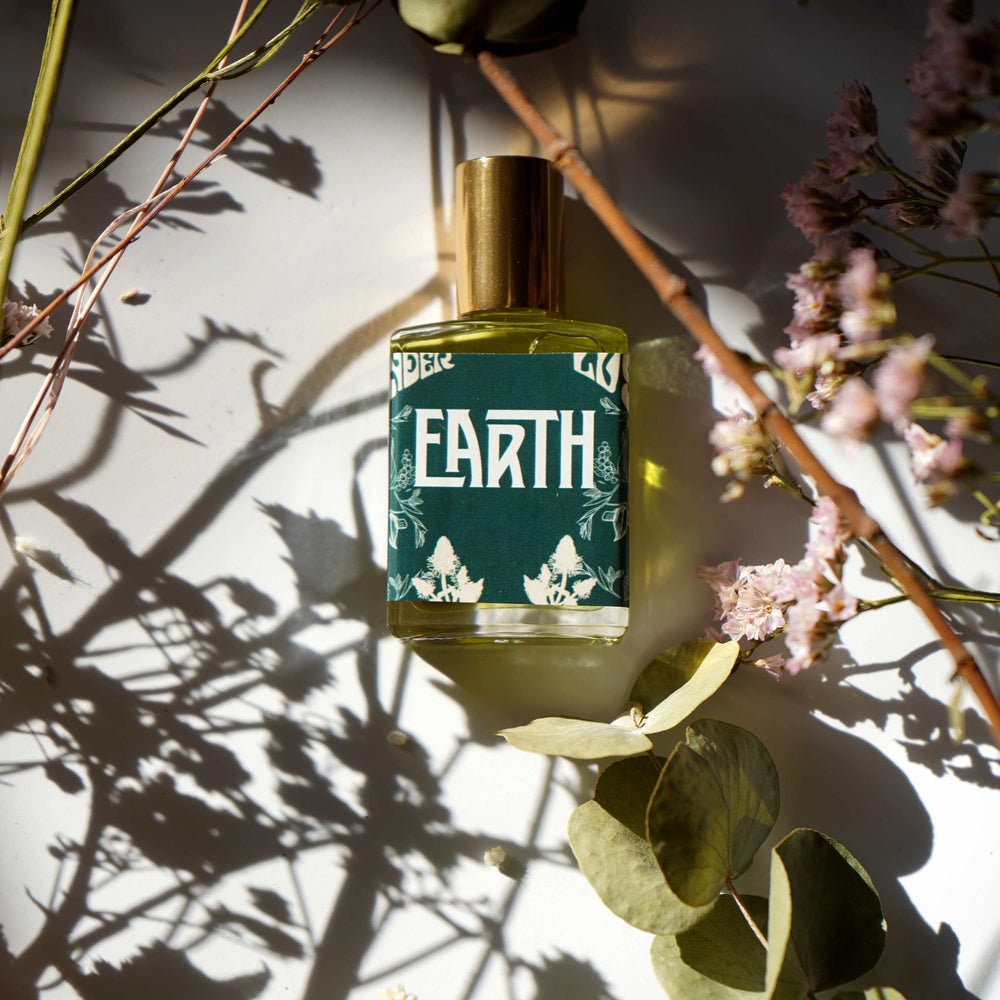 Wonderlust Botanicals Earth Oil Perfume – unisex aromatherapy blend with patchouli, cinnamon, and black pepper essential oils in a roll-on bottle.